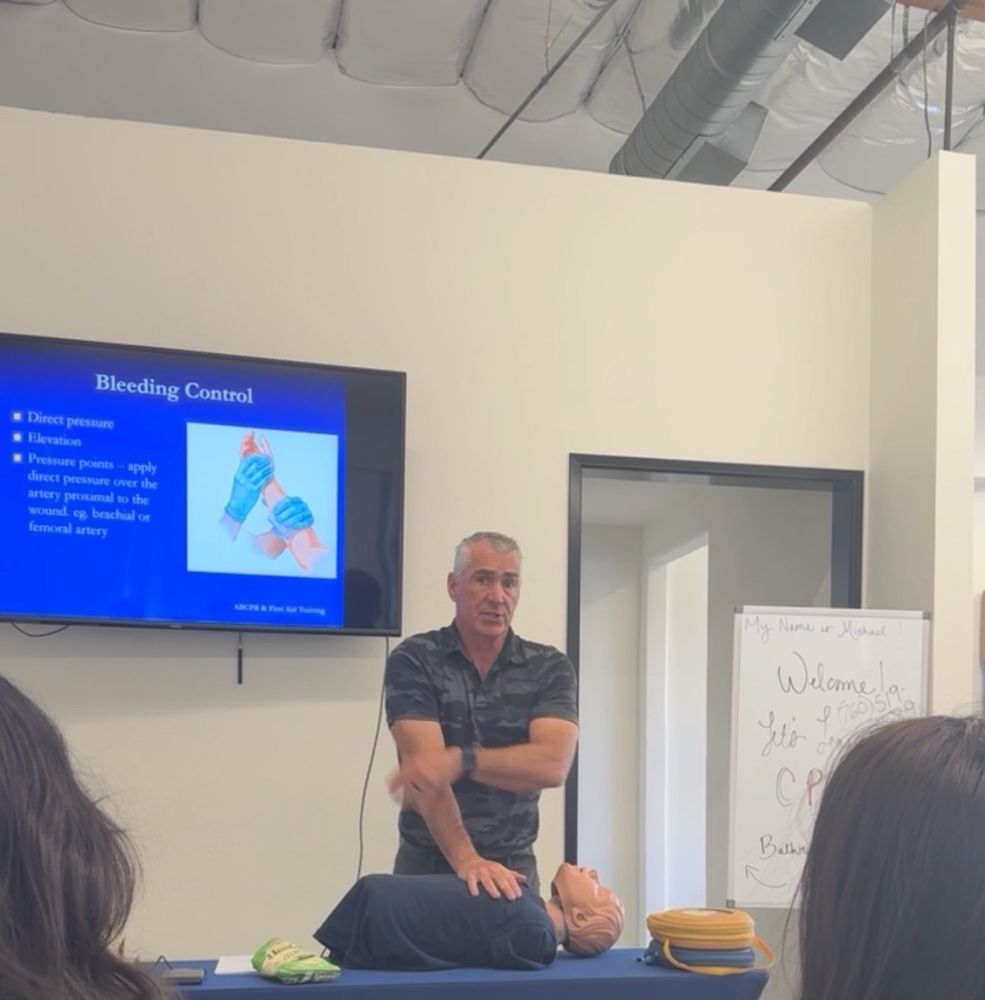 Mike Long teaching bleeding control during an A-B-CPR first aid class, with a CPR manikin and AED on the table